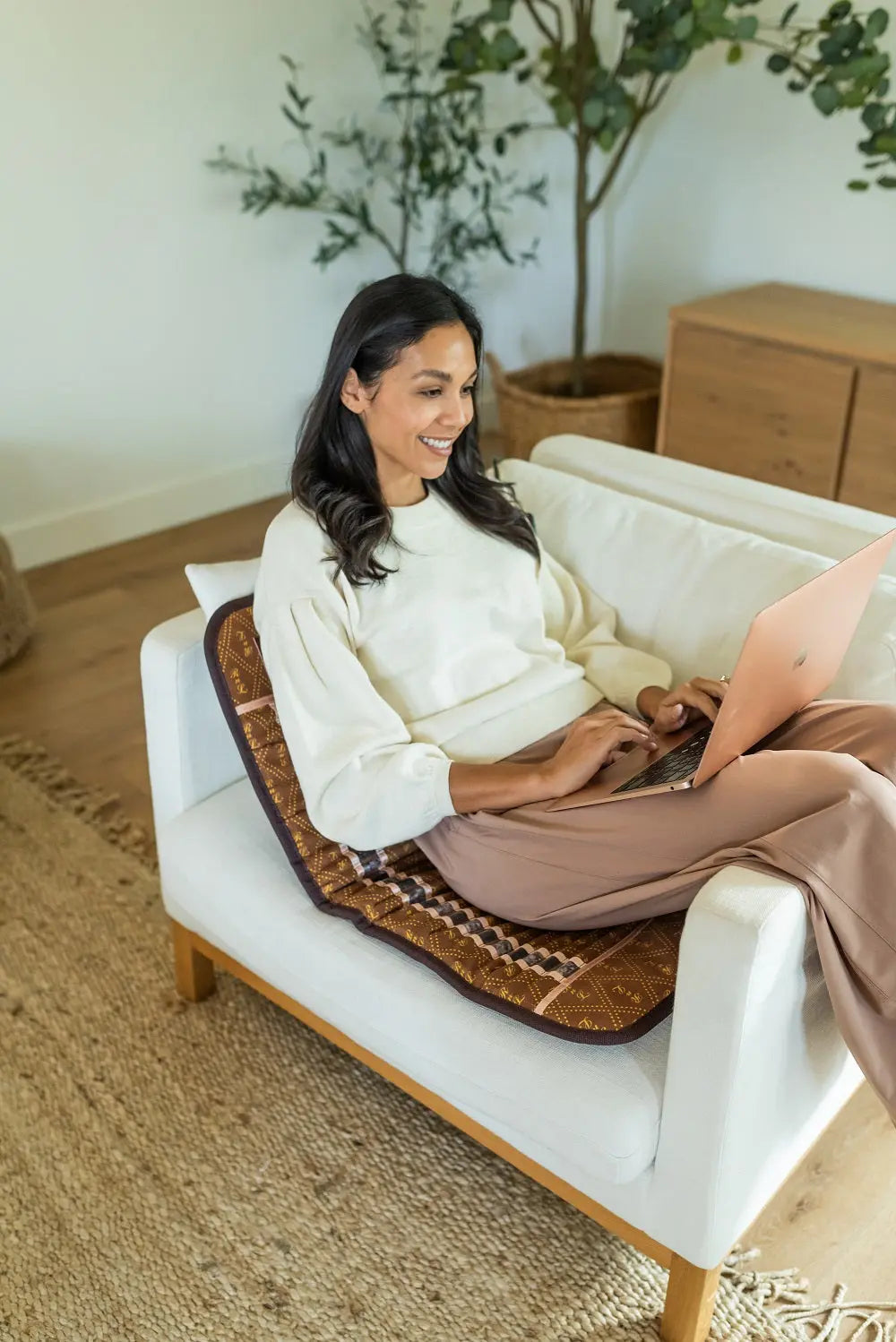 Person using the BioMat Mini portable infrared therapy mat in an armchair while working on a laptop