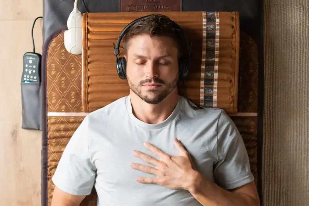 Person wearing headphones and lying on a BioMat