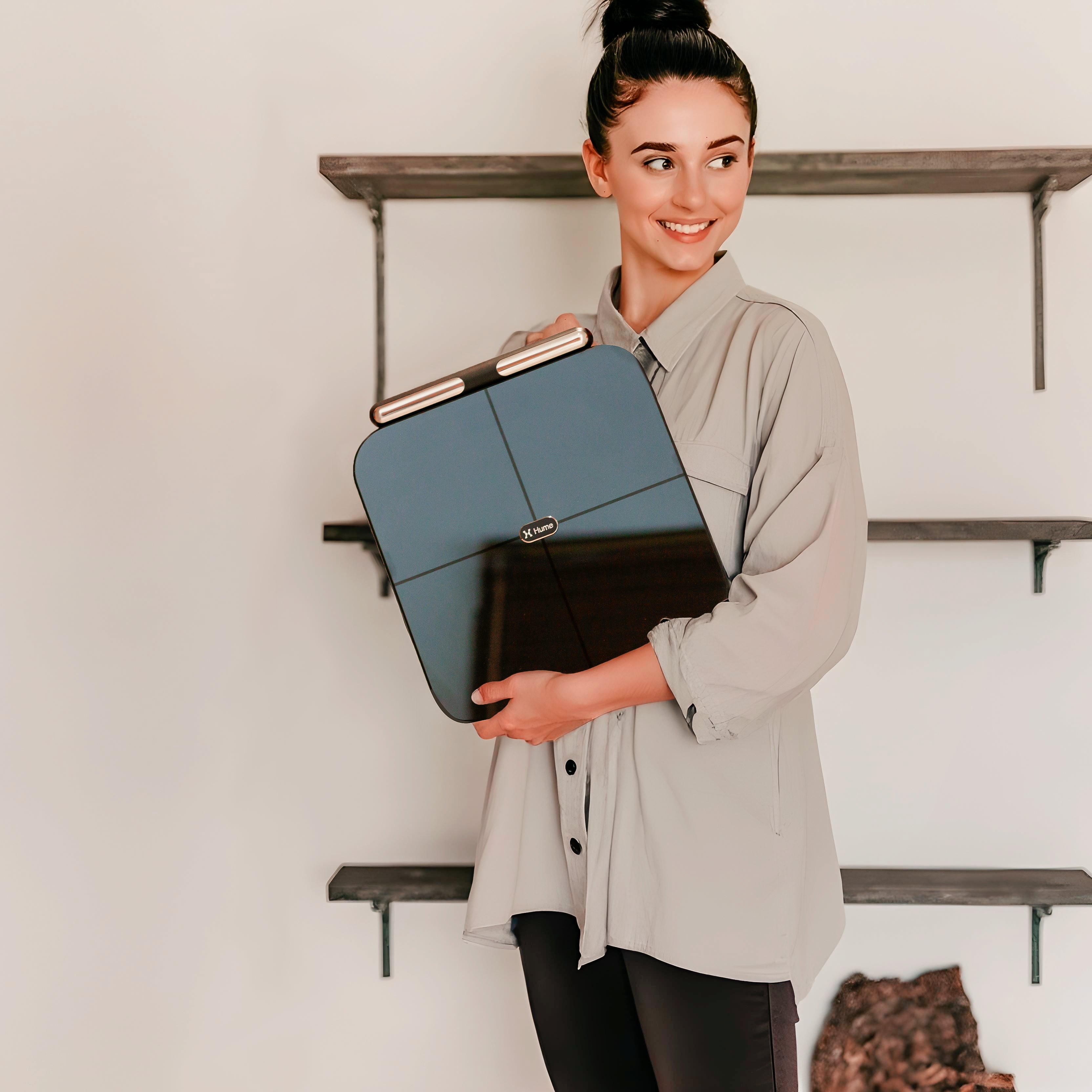 Person holding the Hume Body Pod smart scale indoors