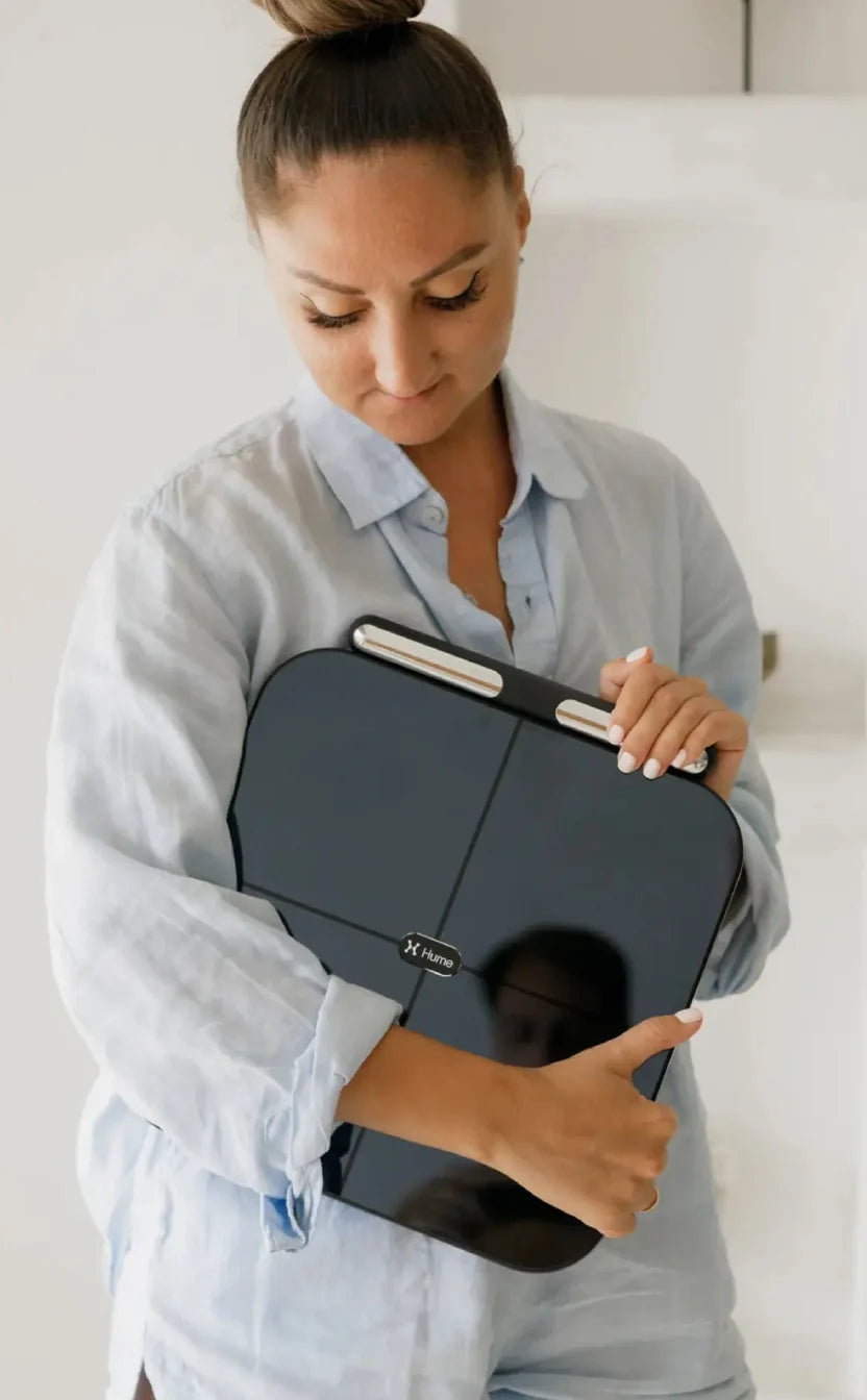 Person holding the Hume Body Pod smart scale against their chest