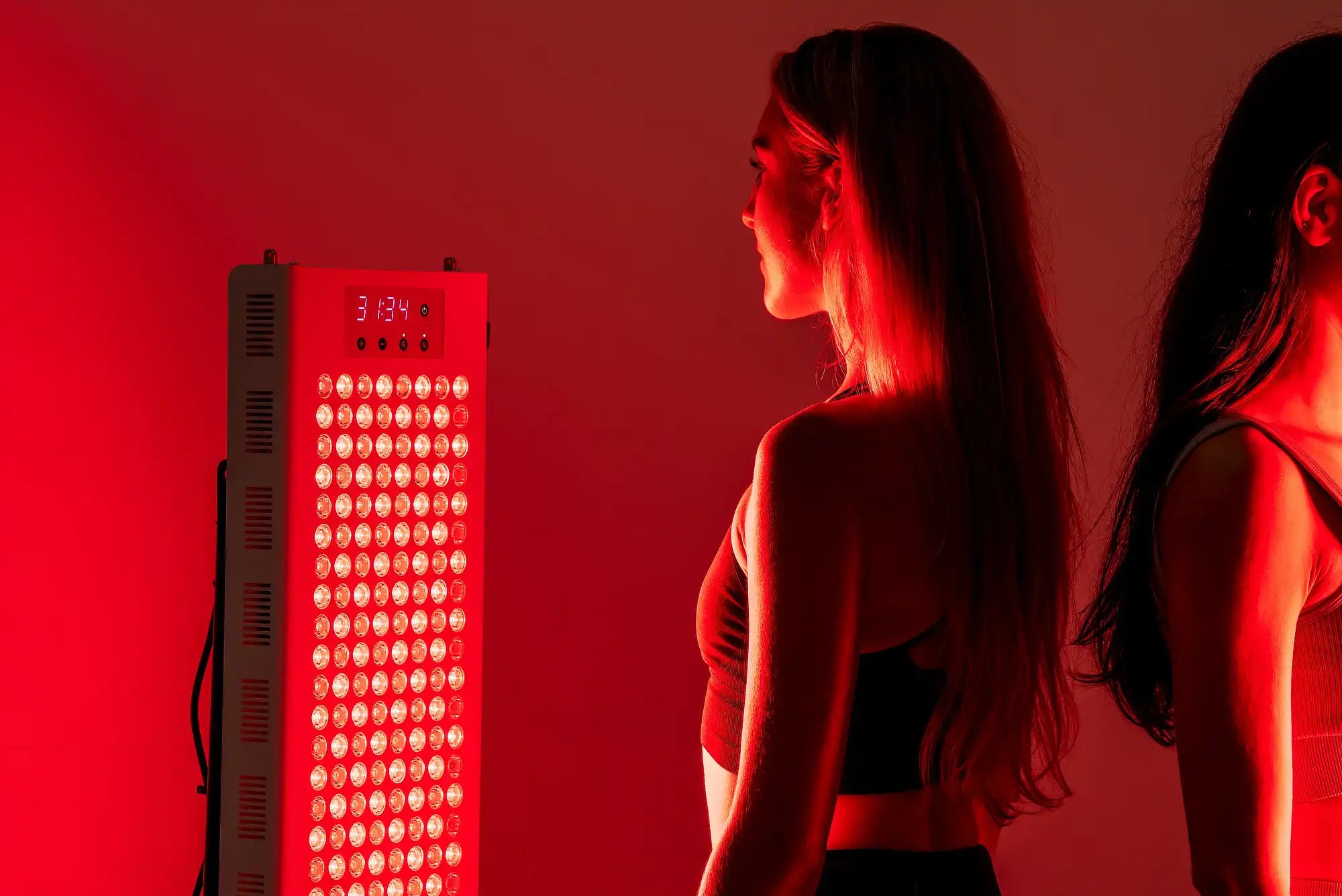 Person standing in front of the illuminated RedRush 840 PULSE full-body red and near-infrared light panel
